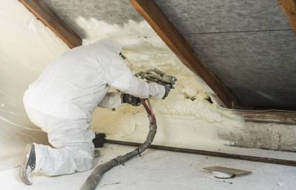 Picture of a person doing spray foam insulation. You can see the person is wearing spray foam insulation kit.